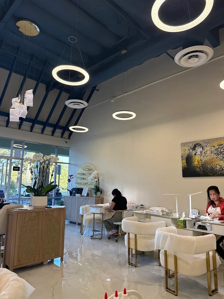 Modern salon interior with round pendant lights, staff at reception desk, and cream-colored seating chairs